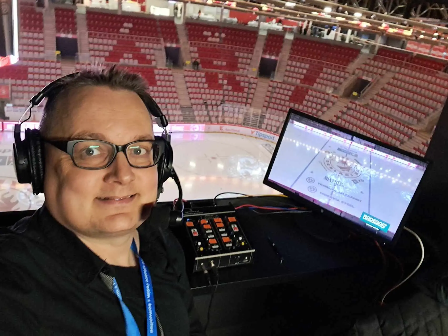 Martin Stebel v komentátorském stanovišti s mikrofonem a výhledem na led WERK ARENY